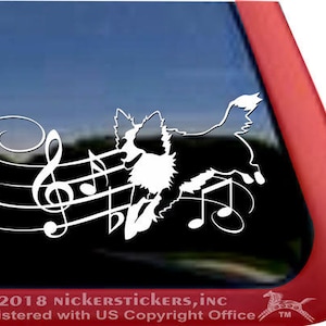 May include: White vinyl decal of a dog silhouette with musical notes. The dog is running and the notes are flowing behind it. The decal is on a black background.
