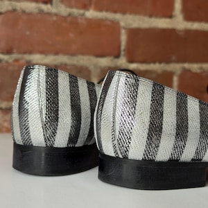 Peut inclure: Gros plan sur deux chaussures &agrave; rayures noires et argent&eacute;es. Les chaussures ont un petit talon et une semelle noire. Le motif ray&eacute; est vertical et recouvre l'ensemble de la tige de la chaussure.