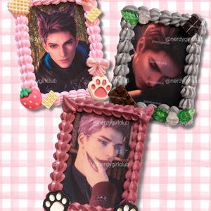 May include: Three rectangular photo frames decorated with textured piping resembling frosting. One frame is pink with a strawberry, waffle, and paw print. One is grey with chocolate and leaves. One is mauve with two black and white paw prints.