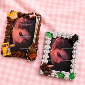 Puede incluir: Dos marcos de fotos rectangulares decorados con nata montada artificial. El marco izquierdo tiene crema marrón, un dije de cupcake amarillo, un hueso rosa y una cuchara plateada con trozos de chocolate. El marco derecho tiene crema blanca y chocolate.