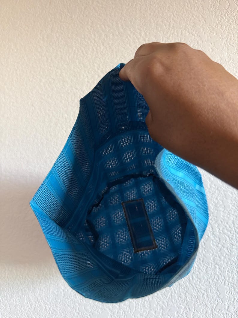 May include: A bright blue cap featuring a structured, grid-like woven texture. The headwear has a distinct geometric pattern throughout the fabric, with a rectangular patch visible on the interior lining of the crown, showcasing a mesh-like construction.