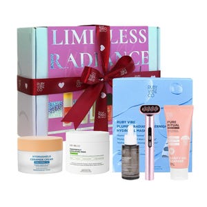 May include: A gift set with skincare products, including a cream, pads, serum, a facial massager, and a cleanser. The box is pink and white with the words "LIMITLESS RADIANCE". A red ribbon is tied around the box.