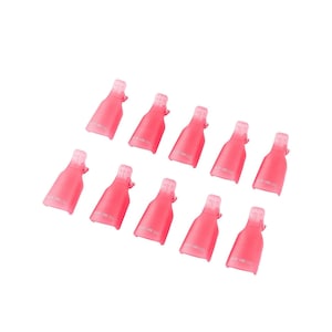 May include: A set of ten pink plastic nail polish remover clips. Each clip has a bottle-like shape with a hinged top. The clips are arranged on a white background.