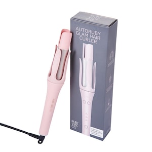 May include: A pink AUTORUBY Glam Hair Curler with a black power cord and a gray box. The curler has a cylindrical design with a pink handle and a silver-colored curling chamber. The box features the product name and a diagram.