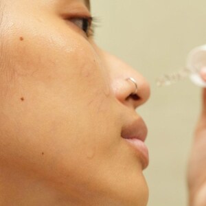 Model applying Ruby Vibe Co Radiant Boost Serum to cheek, lightweight texture absorbs quickly for dewy radiance.
