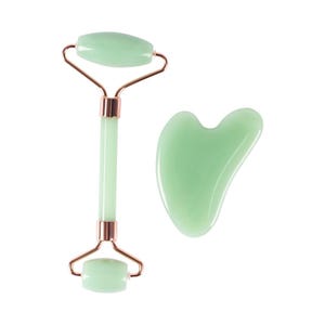 May include: A jade facial roller and a gua sha tool. The roller has a light green stone with rose gold metal accents. The gua sha tool is a light green, heart-shaped stone.