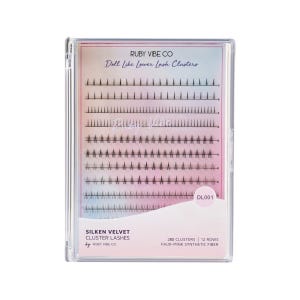 May include: A clear plastic case containing Silken Velvet cluster lashes. The package features the text "RUBY VIBE CO" and "Doll Like Lower Lash Clusters." The lashes are black and arranged in rows. The package also states "280 Clusters | 12 Rows | Faux-Mink Synthetic Fiber."