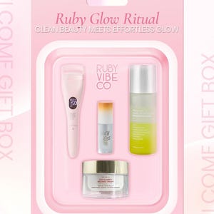 May include: A pink gift box labeled "Ruby Glow Ritual" containing beauty products. Includes an eyelash curler, a lip product labeled "Juicy Kiss", a makeup remover, and a jar of "Cica Clarify Balance Cream". The box is pink with white text.