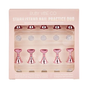May include: A pink and silver nail art practice duo set. The set includes a magnetic nail art display and practice stand with five pink magnetic nail holders. The packaging includes the text "RUBY VIBE CO" and "STARILISTAND NAIL PRACTICE DUO".
