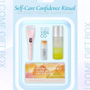 May include: A self-care gift set in a light blue package. The set includes a pink eyelash curler, a small lip gloss, a clear bottle with a yellow liquid, and a box labeled "Ruby Vibe Co. Moonlit Elegance Glass Jelly Cat Eye Set."