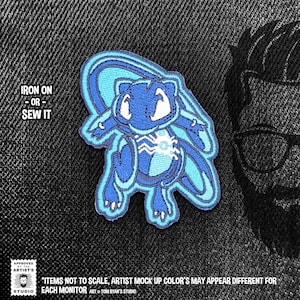 May include: Blue and turquoise embroidered iron-on or sew-on patch featuring a cartoon character with a large head and a small body. The text "IRON ON -OR- SEW IT" is visible at the top of the image.