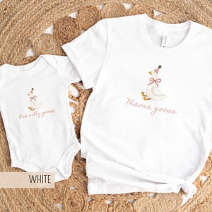 May include: White t-shirt and onesie set. The t-shirt has the words "Mama goose" and the onesie has the words "One silly goose" in a pink script. Both garments feature a cartoon goose wearing a party hat and bow.