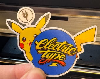 May include: A die-cut sticker featuring a yellow cartoon character with long ears and red cheeks, holding a blue circular sign that says Electric type in yellow and red script. Above the character is a small speech bubble with a black plug icon.