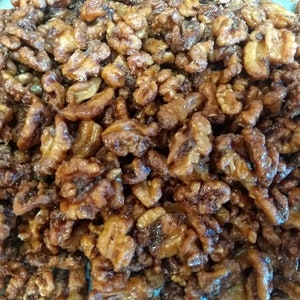 May include: A close-up of a large bowl of candied walnuts. The walnuts are coated in a thick, golden-brown glaze.