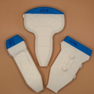 Op de afbeelding: Drie witte medische echotransducers met blauwe accenten. De transducers hebben verschillende vormen en maten, met labels zoals "C1-5", "3SC" en "L4-12t" in blauw.