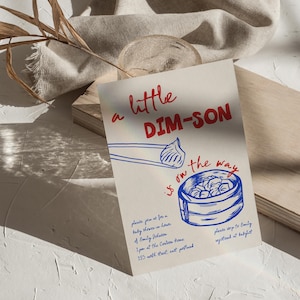 以下が含まれることがあります： クリーム色のベビーシャワーの招待状。赤と青のテキストで「a little DIM-SON is on the way」と書かれています。点心のイラストが特徴です。イベントの詳細も含まれています。