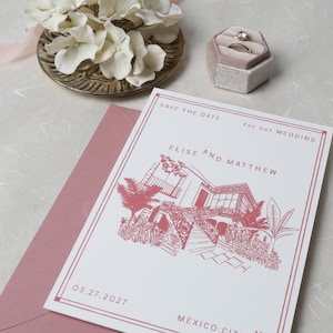 May include: A white save the date wedding card with dusty rose ink featuring a line drawing of a house with palm trees, text reading Elise and Matthew, 03.27.2027, and Mexico City, placed on a dusty rose envelope next to a ring box and white flowers.