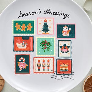 May include: White ceramic plate with a festive design featuring postage stamp illustrations of gingerbread men, a Christmas tree, and a snowman. The plate is decorated with the text "Season's Greetings".