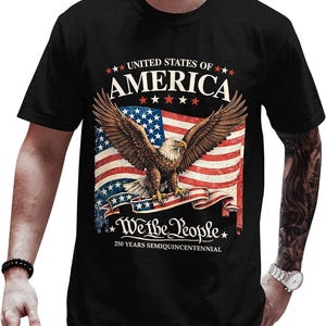 May include: Black t-shirt featuring a patriotic design. The graphic includes a bald eagle with outstretched wings in front of an American flag. Text reads "UNITED STATES OF AMERICA" and "We the People" with "250 YEARS SEMIQUICENTENNIAL".