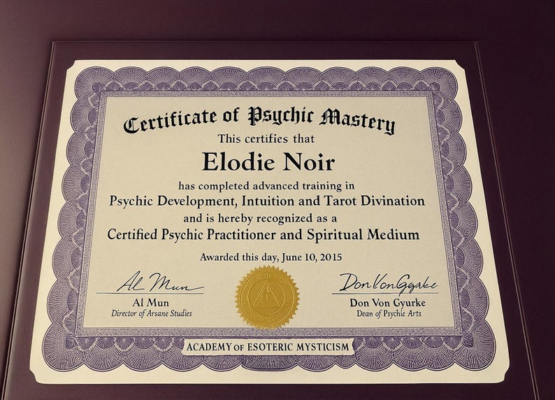 Op de afbeelding: Ingelijst certificaat van Psychic Mastery, toegekend aan Elodie Noir. Het certificaat, met een decoratieve rand, erkent een gevorderde opleiding in psychische ontwikkeling, intu&iuml;tie en tarotdivinatie. Ondertekend door Al Mun en Don Von Gyurke, gedateerd 10 juni 2015.
