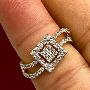 Puede incluir: Un anillo de oro con un dise&ntilde;o cuadrado incrustado de diamantes. El anillo presenta una doble banda y un cuadrado central lleno de diamantes m&aacute;s peque&ntilde;os. Los diamantes brillan sobre el oro, creando un aspecto lujoso.