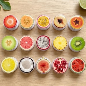 May include: A collection of round phone grips featuring colorful fruit designs. The grips showcase sliced strawberries, cantaloupe, passion fruit, peach, papaya, honeydew, grapefruit, dragon fruit, pineapple, kiwi, lemon, coconut, fig, pomegranate, and watermelon.