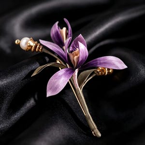 May include: A floral brooch featuring purple petals with a light center, accented by a white pearl bead on a gold-toned stem. The design includes slender green leaves and metallic gold-toned details, showcasing a botanical arrangement.