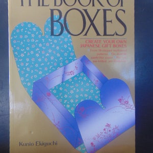 May include: The Book of Boxes: Create Your Own Japanese Gift Boxes.  A book cover with a gold background and a blue and green box with a floral pattern. The book title is in black text and the author's name is in black text at the bottom of the cover.