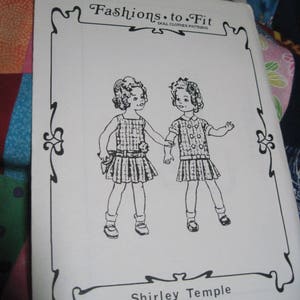 May include: Black and white illustration of two girls wearing dresses. The illustration is on a white sheet of paper with a black border. The text "Fashions to Fit Doll Clothes Patterns" is at the top of the page. The text "Shirley Temple 02/15/2016 03:02" is at the bottom of the page.