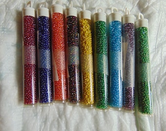 May include: Ten small tubes of seed beads in various colors, including red, blue, orange, green, and yellow. The beads are iridescent and have a shiny finish.