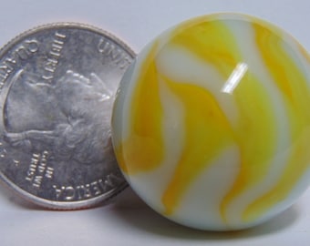May include: A white and yellow marble with a swirling pattern. The marble is about the size of a quarter.