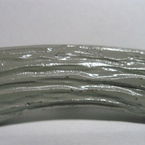 May include: A gray, curved, wooden-style knob with a textured surface. The knob is designed to resemble a tree branch.