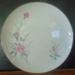 May include: A white ceramic plate with a gold rim features a delicate floral design of pink roses and green leaves.