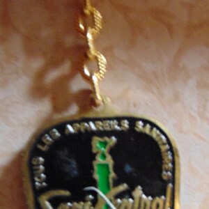 May include: Gold keychain with a black and green enamel charm. The charm features the text "Sous Les Appartements Saints" and "Saint-Sulpice" with the words "Basilique" and "Paris 1678-1978" in smaller text.