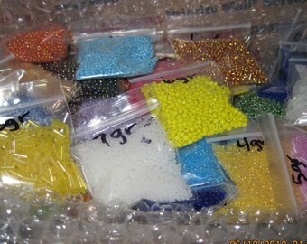 May include: A variety of colorful beads in small plastic bags. The bags are labeled with the weight of the beads in grams. The beads are a mix of different shapes and sizes.