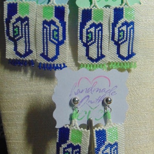 May include: Three pairs of handmade earrings with blue, green, and white beaded designs. The earrings are on white cards with the text "handmade with love".