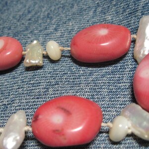 May include: A pink and white beaded necklace with pink oval beads and white shell beads.