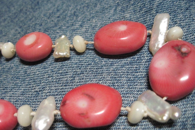 May include: A pink and white beaded necklace with pink oval beads and white shell beads.