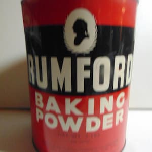 May include: Vintage Rumford Baking Powder tin. The cylindrical container features a red top and bottom with a black band in the middle. The brand name is in large white letters, with the words "Baking Powder" below. A white silhouette is in the center.