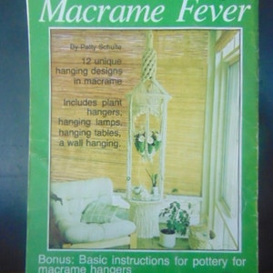 May include: A green book cover with the title "Macrame Fever" by Patty Schulte. The book features 12 unique hanging designs in macrame, including plant hangers, lamps, tables, and a wall hanging. It also includes basic instructions for pottery for macrame hangers.