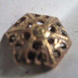 May include: A gold-toned metal decorative piece with a hexagonal shape and intricate cut-out design.