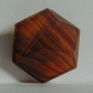 May include: A faceted, hexagonal object with a warm color palette of amber, brown, and orange. The object's surface has a striped pattern, with the colors blending together. The geometric shape and color variations create a visually interesting piece.