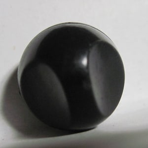 May include: A black round knob with a smooth, shiny surface.