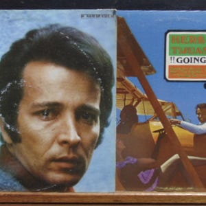 May include: Two vinyl record album covers. The left cover features a portrait of a man with the text Sounds Like Herb Alpert and the Tijuana Brass Casino Royale. The right cover shows a yellow biplane with the text Herb Alpert and the Tijuana Brass Going Places.