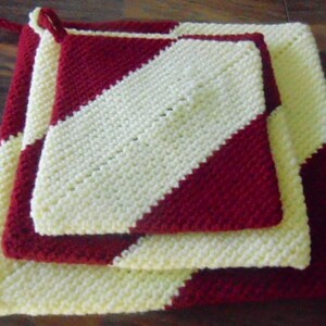 May include: Three crocheted pot holders in red and white stripes. The pot holders are layered on top of each other, with the largest one on the bottom and the smallest one on top.