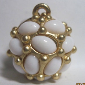 May include: A gold-toned pendant with a round shape and white oval-shaped stones. The pendant has a loop at the top for attaching to a chain.