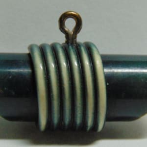 May include: A dark green ceramic pendant with a white and green striped design. The pendant has a gold loop at the top for hanging.