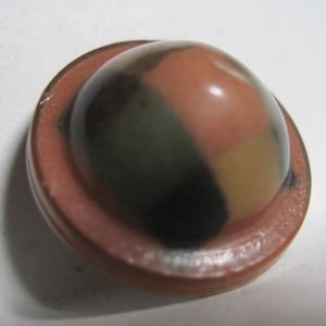 May include: A round, dome-shaped button with a brown rim and a multi-colored, mottled surface. The colors are shades of brown, green, and black.