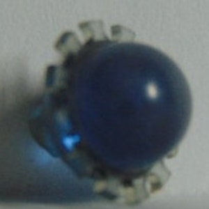 May include: A blue glass bead with a clear, faceted, plastic setting.