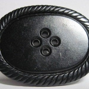 May include: Black oval button with a rope-like border and four holes in the center.